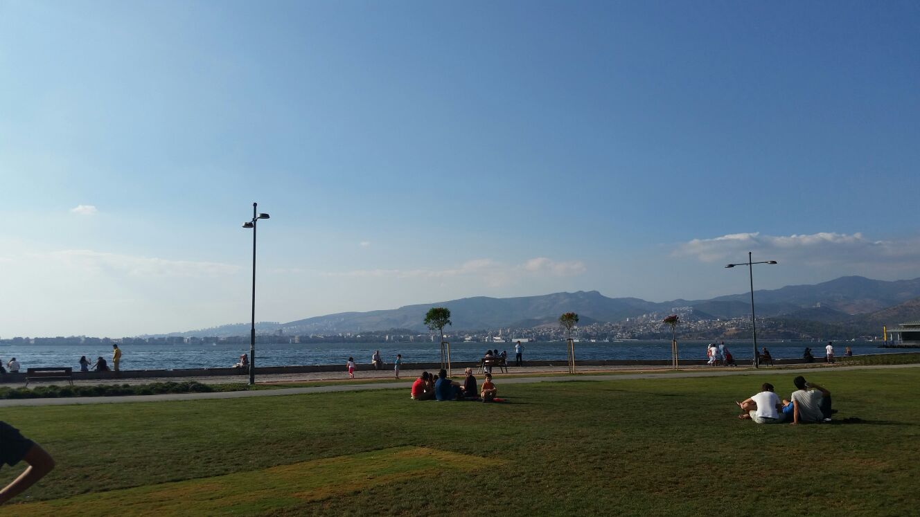 İzmir Kordon’da deniz kıyısı ve çimlerde dinlenen insanlar